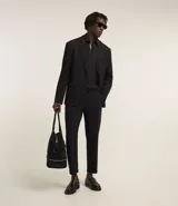 Pantalón de vestir para hombre, color beige claro, de corte slim y sastrería. Presenta cierre frontal con botón y cremallera, y bolsillos laterales y traseros.