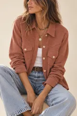 Camisa de pana color terracota, con cierre frontal de botones, bolsillos con solapa en el pecho y cuello camisero.