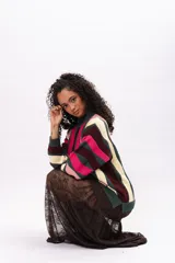 Buzo de tejido de punto con diseño de rayas verticales multicolores en tonos verde oscuro, fucsia, rosa claro y crema. Presenta cuello redondo, puños y ruedo acanalados.