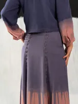 Chaqueta entallada de algodón tipo seda, teñida a mano con técnica tie-dye en tonos azul y naranja. Tiene cuello mao, mangas largas con puños abullonados y cierre frontal con broches.