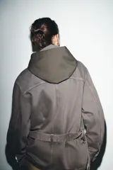 Capucha de diseño estructurado con exterior liso y forro interior con estampado de cuadros. Presenta un cierre frontal con lazada.