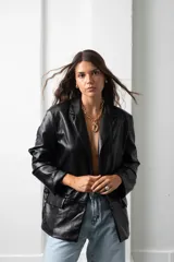 Blazer de eco cuero negro con hombreras, solapas clásicas y cierre frontal con botones.