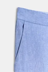 Pantalón de vestir celeste confeccionado en hilatura con lino, de tiro medio con bolsillos delanteros y falsos bolsillos traseros. Tiene abertura lateral en el bajo y cierre frontal con cremallera y ganchos metálicos.