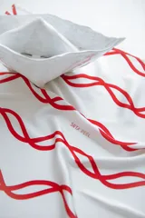 Pañuelo de seda blanco con estampado de ondas entrelazadas en rojo. Presenta la inscripción "SRTA PEEL" en rojo.
