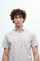 Camisa de manga corta confeccionada en tela 100% algodón con estampado de cachemir en tonos naranja y celeste. Tiene un bolsillo en el pecho y botones personalizados.