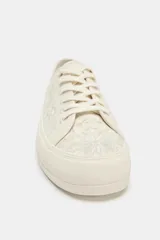 Zapatillas deportivas color crema con bordados florales. Cierre con cordones y punta redonda.