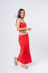 Pollera larga de color rojo, con diseño de corte recto y tajo lateral. Presenta una cintura elástica cómoda y un acabado satinado.