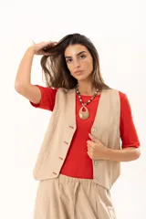 Chaleco de corte sastre en color beige, con escote en V, cierre frontal mediante botones y costuras decorativas en contraste.