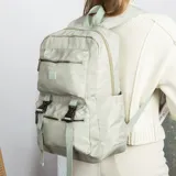 Mochila de gran capacidad color beige, confeccionada en nylon. Cuenta con múltiples compartimentos frontales con cierre y hebillas ajustables, bolsillos laterales y correas acolchadas para mayor comodidad.