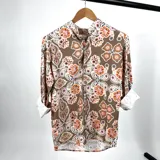 Camisa de manga larga con cuello mao y estampado de arabescos en tonos beige, naranja y rosa.