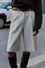 Bermuda larga color marrón oscuro, tiro medio, con pinzas frontales y cinturón de textura animal print plateado.