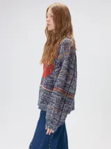 Sweater de punto con diseño geométrico y gráfico frontal en color rojo. Presenta cuello redondo, mangas largas holgadas y un ajuste suelto.