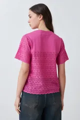 Remera fucsia de manga corta con detalle de broderie en las mangas.