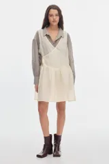 Vestido corto fluido de tacto sedoso en color marfil, con escote en V cruzado, sin mangas y falda con volados en la parte inferior.