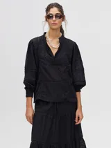 Camisa de broderie de algodón color negro, con diseño de calados, cuello mao con cierre de botones, mangas abullonadas con puños fruncidos y detalles de galones con transparencias.