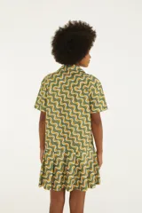 Vestido corto de algodón con estampado geométrico de ondas en tonos verde, amarillo y blanco, con cuello camisero, manga corta y cierre frontal de botones.