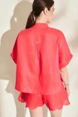 Blusa negra de lino de silueta amplia, con cuello mao y doble hilera de botones dorados en el frente. Cuenta con mangas cortas con vuelta.