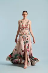 Vestido largo color rosado con escote en V pronunciado, sin mangas, talle ajustado con bordados florales y falda larga vaporosa con tajo frontal y estampado floral y de mariposas.
