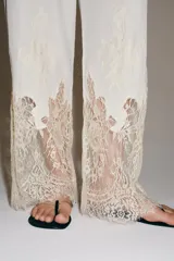 Pantalón de tiro medio con cintura elástica ajustable mediante cordones. Presenta un diseño fluido con bolsillos laterales ocultos y bajo decorado con una aplicación de encaje a contraste.