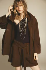 Trench color marrón confeccionado en mezcla de lyocell y lino. Cuello solapa y manga larga. Bolsillos con solapa en delantero. Cierre frontal con botones a presión.