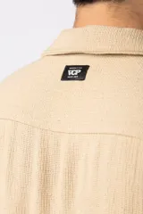 Camisa de manga corta con cuello cubano, confeccionada en lino entramado de textura natural. Presenta un corte relajado y cierre frontal con botones.