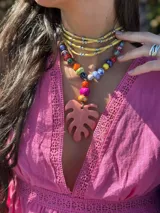 Collar corto con cuentas de cerámica y acrílico de colores, tiento sintético y dije de resina en forma de hoja de palmera color coral.