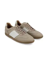 Championes de cuero color beige con franja lateral blanca, cordones al tono y suela de goma color caramelo.