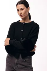 Chaqueta tejida de silueta recta con botones frontales y puños con textura suave tipo piel. Diseño versátil que permite usarla con los botones en la parte posterior.