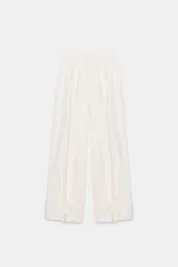 Pantalón fluido de tiro medio, color blanco, con cintura elástica ajustable con cordones, bolsillos laterales y bajo ajustable con trabilla y botón a presión.