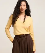 Suéter de punto color amarillo, con escote en V y mangas largas. Presenta un diseño básico y versátil, confeccionado en una mezcla de viscosa, poliamida y elastano.