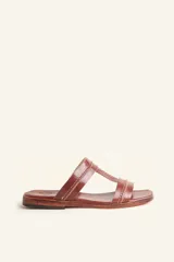 Sandalia plana de cuero color marrón, con tiras anchas y costuras blancas a la vista. Tiene punta cuadrada y un pequeño taco de 2 cm.