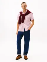 Camisa de manga corta confeccionada en tejido seersucker de algodón BCI a rayas rojas y blancas. Tiene cuello clásico, cierre con botones y logo de Tommy Hilfiger bordado en el pecho.