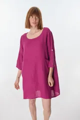 Vestido corto color beige de lino, con cuello redondo, corte oversize y mangas 3/4 con botón. Presenta bolsillos laterales.