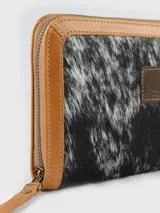 Billetera de cuero con detalles en pelo vacuno con estampado animal print, cierre perimetral y parche de cuero con logo grabado en el centro.