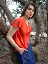 Blusa color naranja de gasa pintada con cuello asimétrico y mangas cortas.
