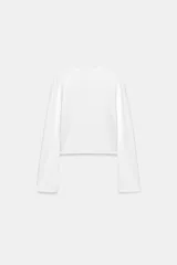 Chaqueta de punto liso color blanco, con cuello redondo, manga larga acabada con cremalleras en los puños y cierre frontal con cremallera.