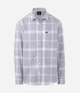 Camisa de franela de manga larga con estampado de cuadros en blanco y negro. Presenta cuello inglés, cierre frontal con botones y bolsillo en el pecho.