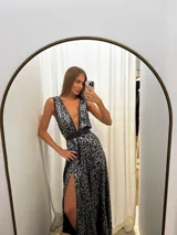 Vestido largo de seda con estampado animal print en tonos plateado y negro, escote en V profundo con ribetes de cuerina, doble cinto que marca la cintura y falda amplia con tajo lateral.