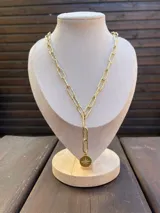 Collar tipo corbatero dorado con cadena de eslabones texturizados y un dije circular colgante con diseño de estrella con circones.