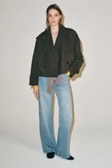 Trench corto Zara Woman Collection confeccionado en hilatura con algodón, en color verde militar. Presenta cuello solapa, manga larga con trabillas y botones en los puños, bolsillos delanteros, bajo asimétrico y cierre frontal cruzado con botones.