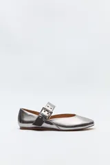Balerina plateada con punta sutilmente afilada y tira ancha con hebilla metálica y ojalillos.