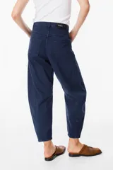 Jean de corte balloon en color azul marino, con cintura alta, cierre frontal con botón y bolsillos laterales. Presenta costuras laterales curvadas que definen su silueta amplia y relajada.