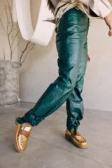 Mocasines de cuero en color dorado con detalles en marrón, con diseño bicolor y costuras artesanales expuestas en el empeine.