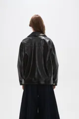 Campera de eco-cuero negro con acabado brillante, cuello camisero, cierre frontal completo y diseño de corte holgado.