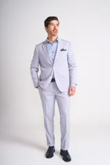 Ambo de dos piezas color gris claro, compuesto por un saco de corte clásico con solapas de muesca y un pantalón de vestir de corte recto con dobladillo en el ruedo.