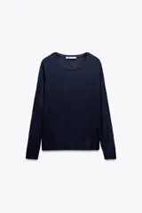 Jersey de punto liso, color azul brillante, con cuello redondo y manga larga. Presenta acabados en rib en puños, cuello y bajo, con aberturas laterales en el ruedo.