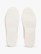 Zapatillas de cuero estilo tenis, color blanco, con cordones y suela de goma al tono. Presentan forro interior en color bordó, ojal superior metálico dorado y logo de monograma TH metálico en el lateral.