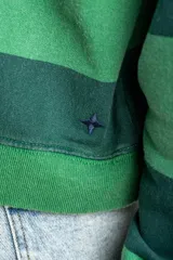 Sweater de algodón peinado con diseño de rayas horizontales en tonos verde oscuro y verde claro, de corte holgado y manga larga, con detalle de bordado en el pecho.