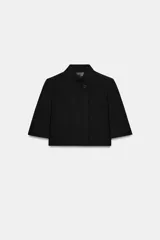 Blazer cropped de corte estructurado, con cuello subido, manga corta y cierre frontal con un botón. Presenta un bolsillo de vivo en el pecho y forro interior a tono.
