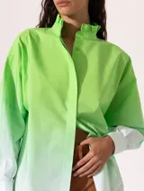 Camisa verde lima con degradé a blanco, de corte holgado, cuello mao con volantes y mangas largas con puños abotonados.
